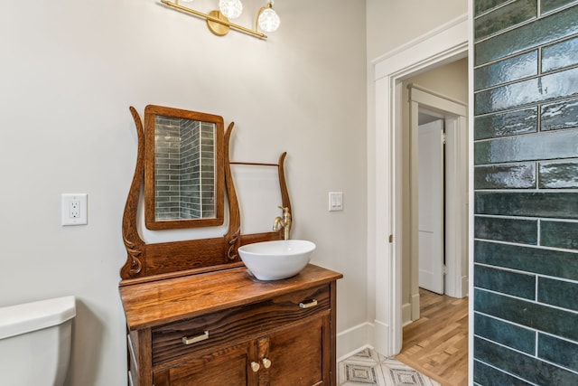 bathroom with toilet, vanity, and wood-type flooring