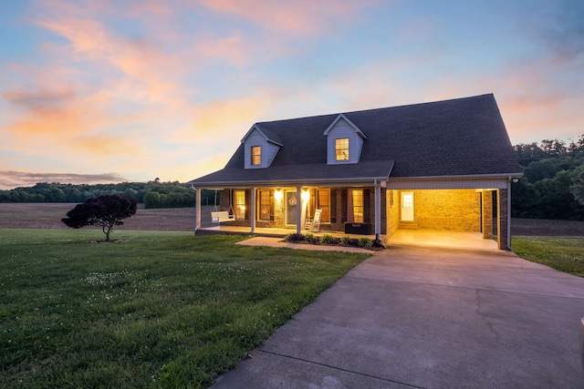 cape cod house with a yard, a carport, and a porch