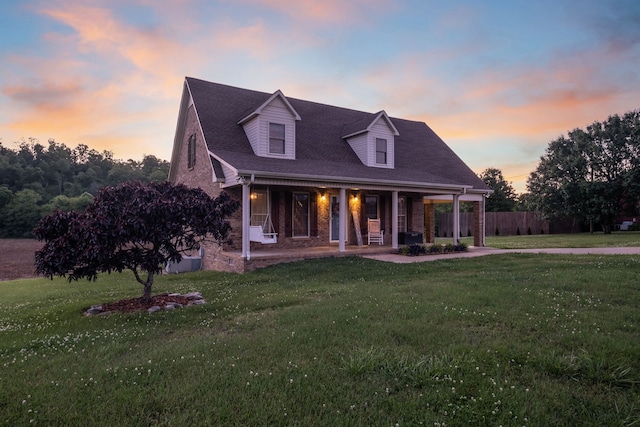 new england style home with a yard and covered porch