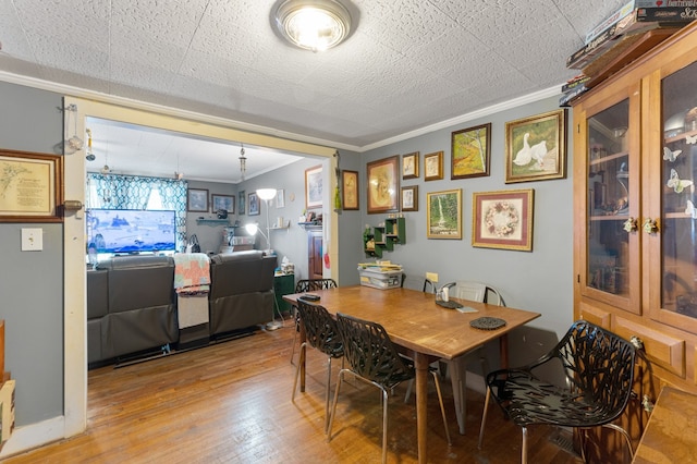 dining area with light hardwood / wood-style floors and ornamental molding