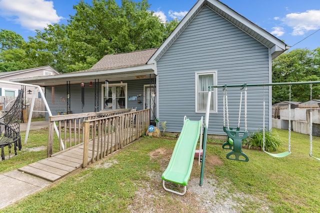 rear view of house featuring a playground and a lawn