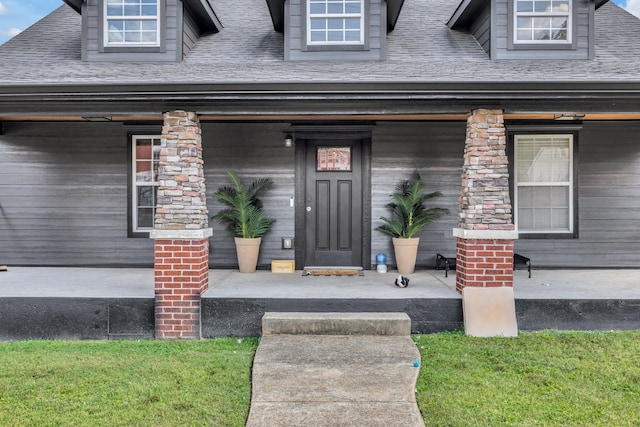 doorway to property with covered porch and a lawn