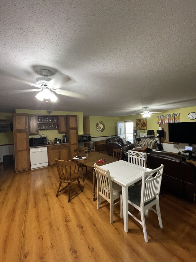 dining room with ceiling fan, hardwood / wood-style flooring, and a textured ceiling