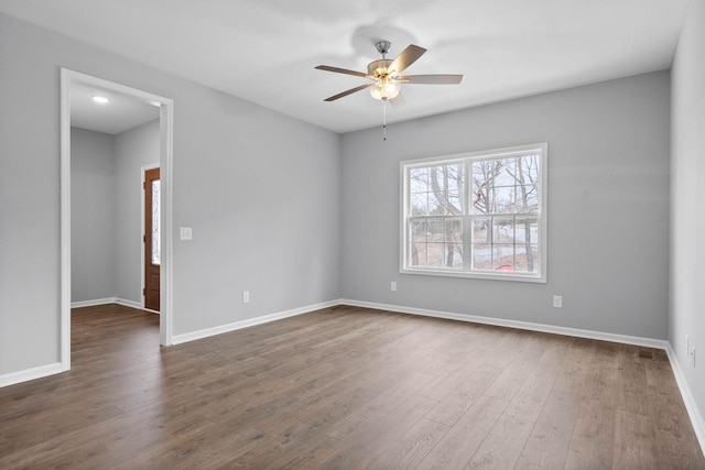 unfurnished room with baseboards, dark wood finished floors, and a ceiling fan