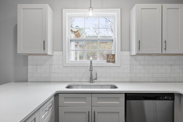 kitchen with stainless steel dishwasher, decorative light fixtures, tasteful backsplash, and a sink