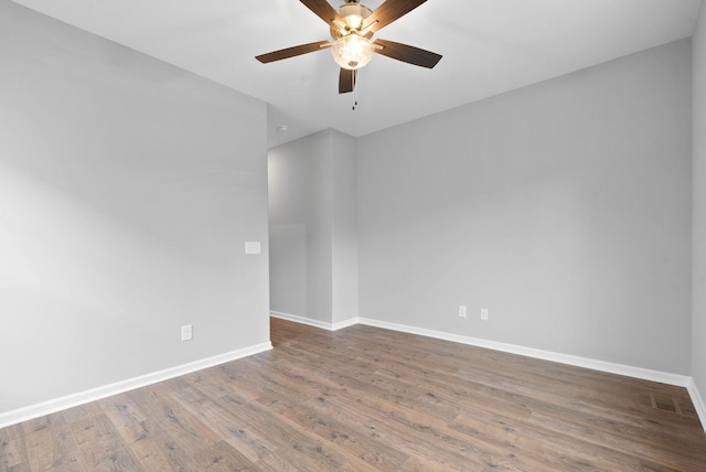 empty room with visible vents, ceiling fan, baseboards, and wood finished floors