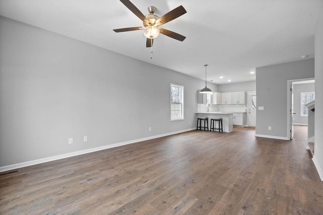 unfurnished living room featuring visible vents, dark wood-type flooring, baseboards, recessed lighting, and a ceiling fan