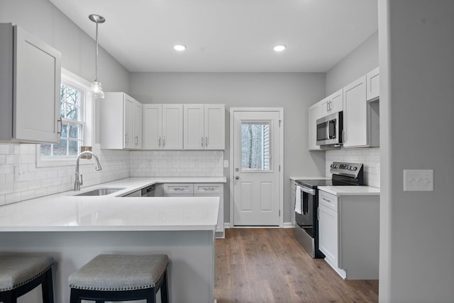 kitchen with a sink, a peninsula, light countertops, and stainless steel appliances