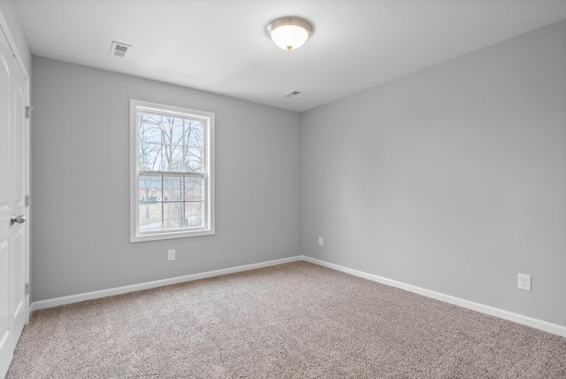 carpeted spare room with visible vents and baseboards