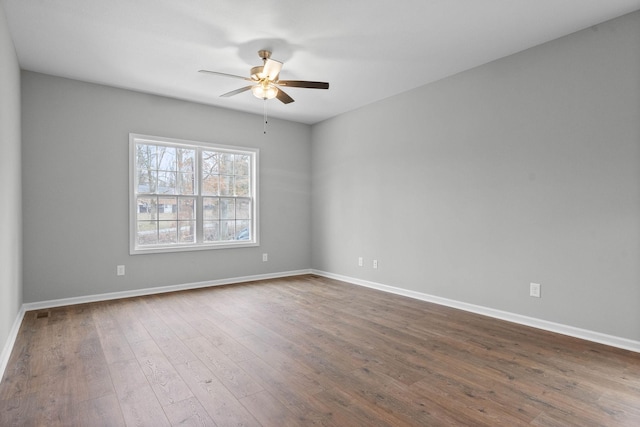 unfurnished room with dark wood-style floors, a ceiling fan, and baseboards