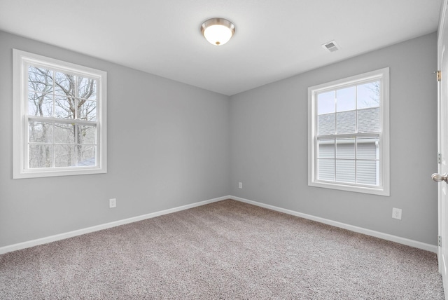 carpeted spare room featuring visible vents and baseboards