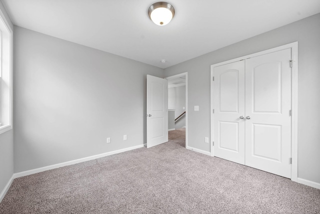 unfurnished bedroom featuring carpet flooring, baseboards, and a closet