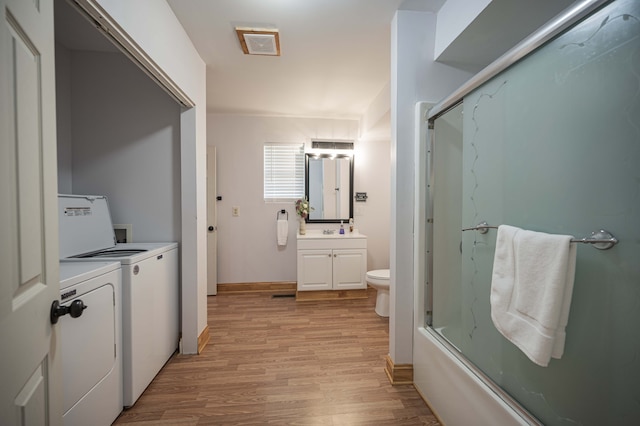 bathroom with toilet, combined bath / shower with glass door, vanity, wood finished floors, and independent washer and dryer