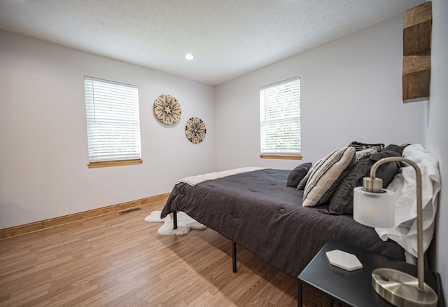 bedroom featuring light wood-type flooring, a textured ceiling, baseboards, and recessed lighting