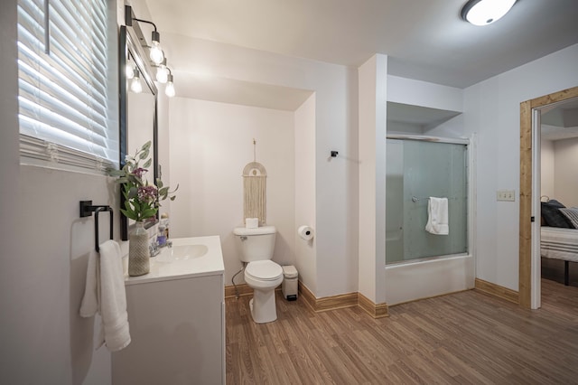 ensuite bathroom featuring toilet, ensuite bathroom, enclosed tub / shower combo, vanity, and wood finished floors