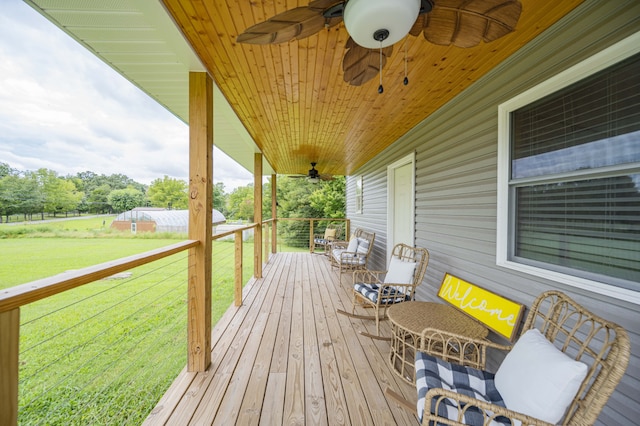 wooden terrace featuring ceiling fan and a lawn