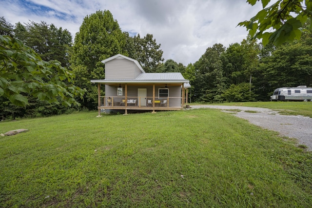 farmhouse inspired home featuring driveway, covered porch, metal roof, and a front yard