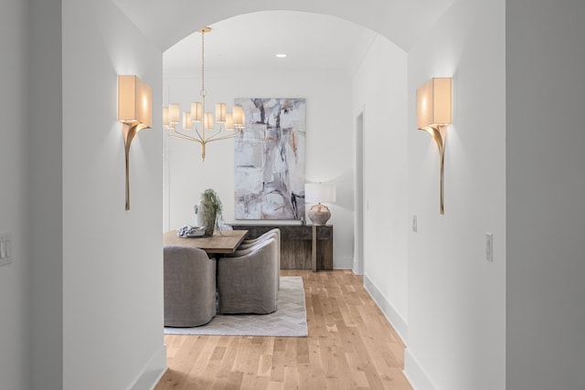 hallway with an inviting chandelier and light wood-type flooring