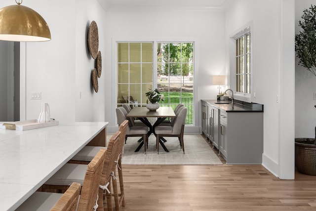 dining area featuring sink, light hardwood / wood-style flooring, and crown molding