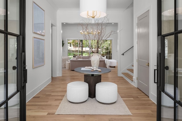 interior space with a notable chandelier, ornamental molding, and light wood-type flooring