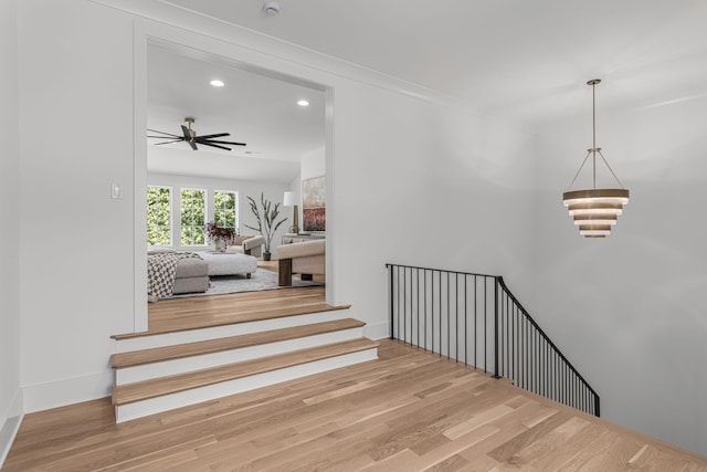 stairs featuring ceiling fan and light hardwood / wood-style flooring