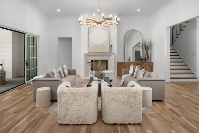 living room with light hardwood / wood-style floors, ornamental molding, and a notable chandelier