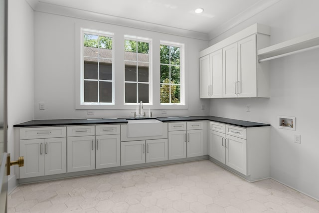 kitchen with a wealth of natural light, sink, ornamental molding, and light tile floors