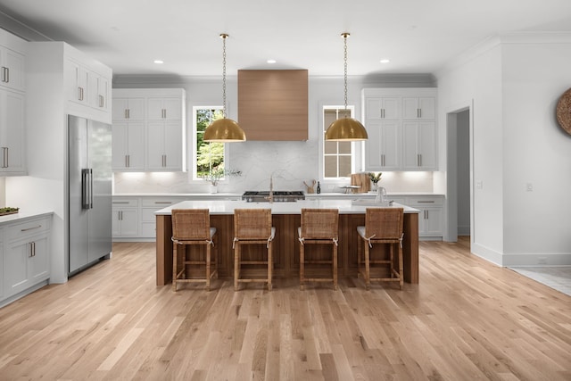 kitchen featuring a center island with sink, high quality fridge, and light wood-type flooring