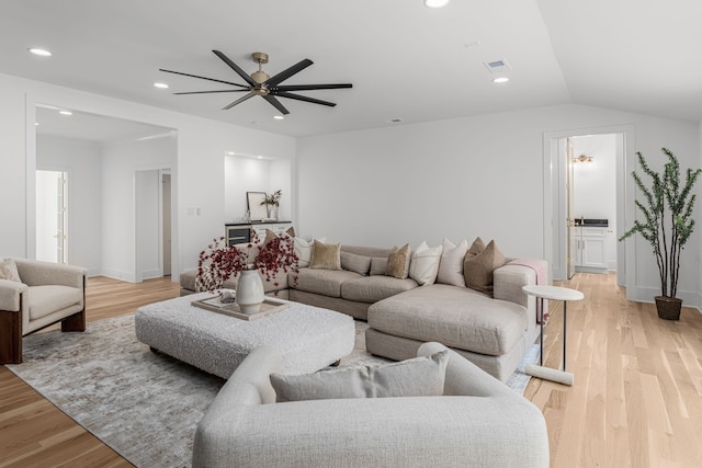 living room with ceiling fan, light wood-type flooring, and lofted ceiling