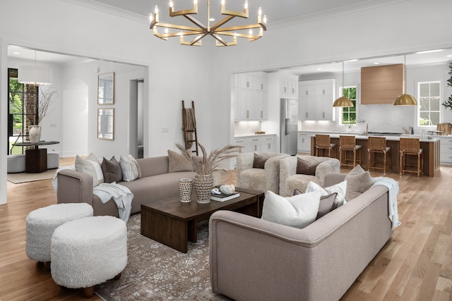 living room with light hardwood / wood-style floors, crown molding, and a notable chandelier