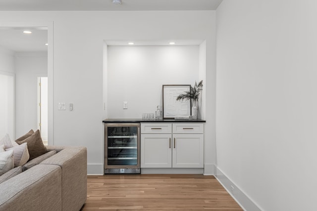 bar featuring wine cooler, light hardwood / wood-style floors, and white cabinetry