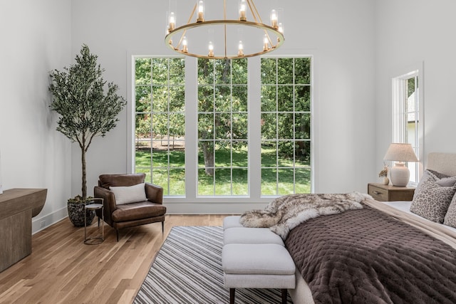 bedroom with a notable chandelier, hardwood / wood-style floors, a high ceiling, and multiple windows