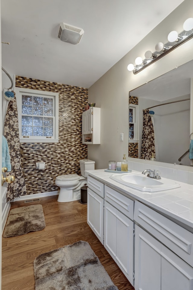 bathroom with tile walls, oversized vanity, toilet, and wood-type flooring