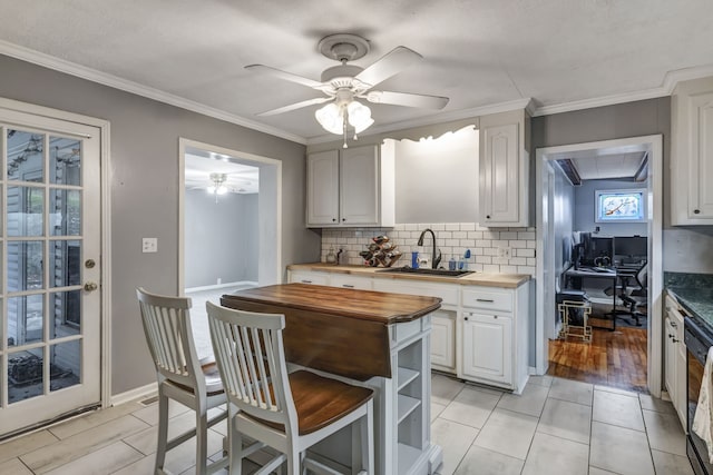 kitchen with backsplash, butcher block countertops, sink, and white cabinetry