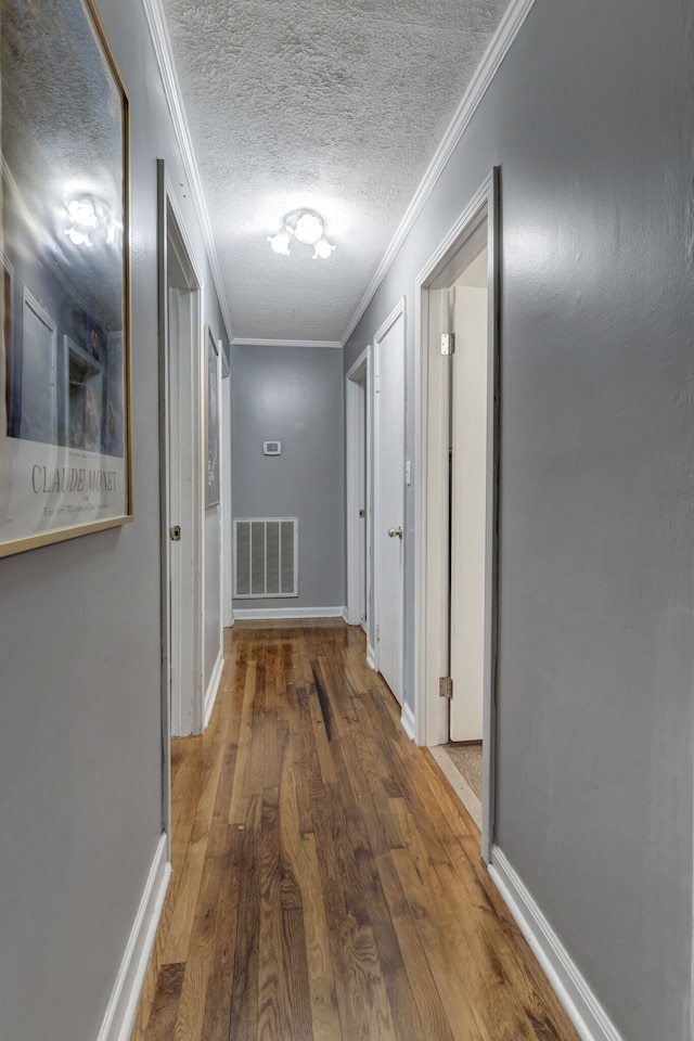 corridor with crown molding, a textured ceiling, and hardwood / wood-style floors