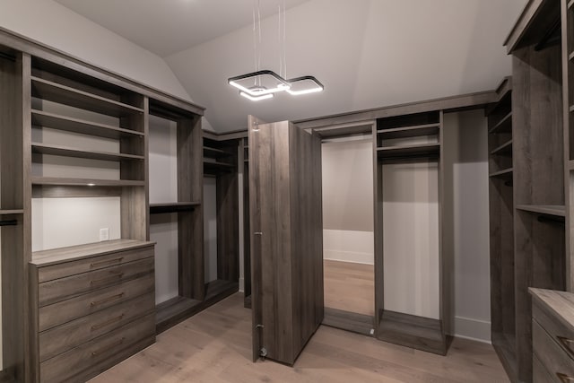 walk in closet with vaulted ceiling and light hardwood / wood-style floors