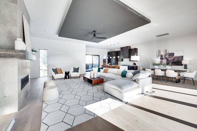 living room featuring ceiling fan, a large fireplace, and light hardwood / wood-style flooring