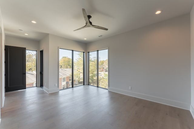 unfurnished room featuring wood-type flooring, plenty of natural light, and ceiling fan