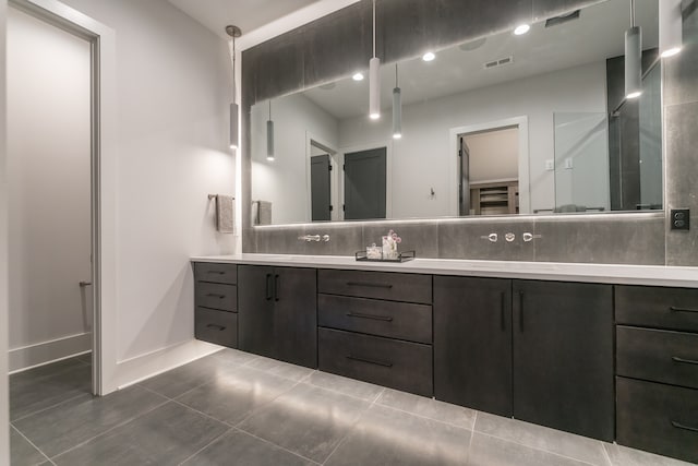 bathroom with tile floors, dual sinks, oversized vanity, and backsplash