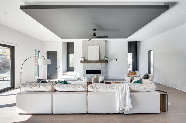 living room featuring ceiling fan, light hardwood / wood-style floors, and a fireplace