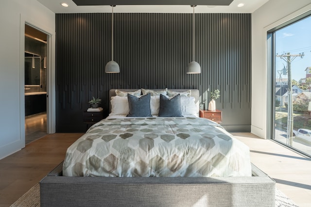 bedroom featuring access to outside, hardwood / wood-style flooring, and ensuite bath