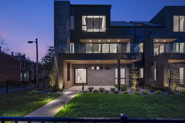 modern home featuring a balcony and a lawn