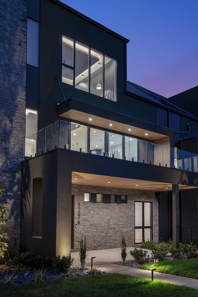 back house at dusk featuring a balcony