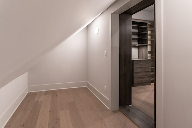 corridor with vaulted ceiling and hardwood / wood-style floors