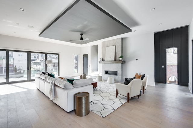 living room featuring plenty of natural light, ceiling fan, light hardwood / wood-style floors, and a large fireplace