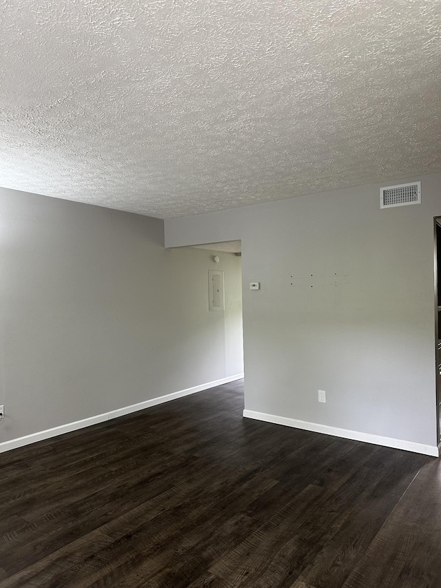 empty room with dark hardwood / wood-style floors, electric panel, and a textured ceiling