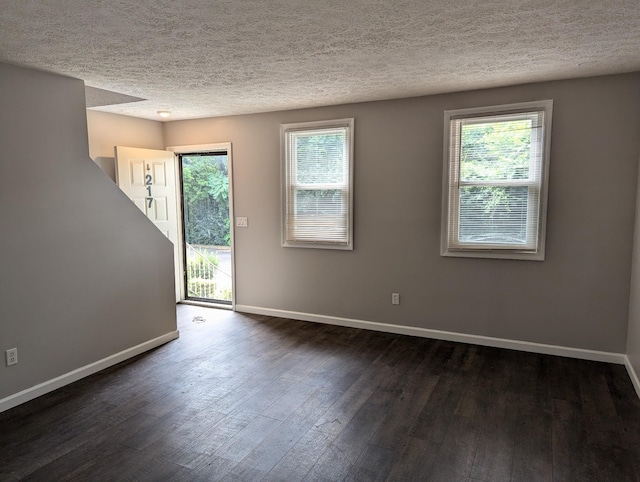 spare room with dark hardwood / wood-style floors and a textured ceiling