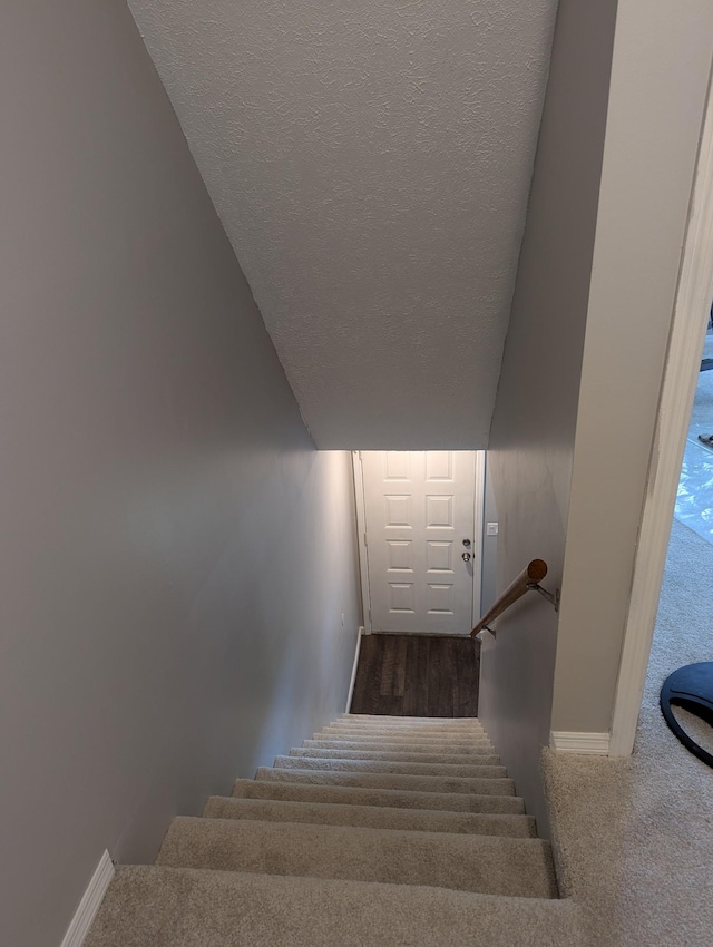 stairs with carpet floors and a textured ceiling