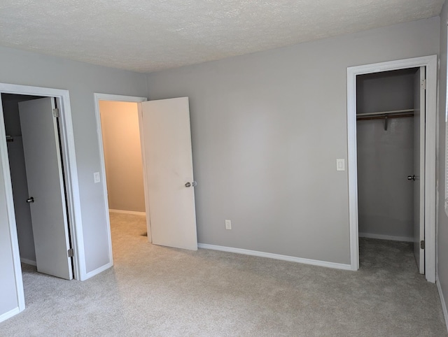 unfurnished bedroom with a spacious closet, light carpet, a textured ceiling, and a closet