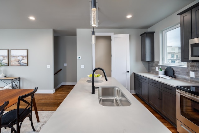 kitchen with backsplash, dark wood-type flooring, appliances with stainless steel finishes, sink, and pendant lighting